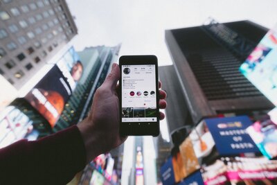 Handy mit geöffnetem Instagram, im Hintergrund der Times Square